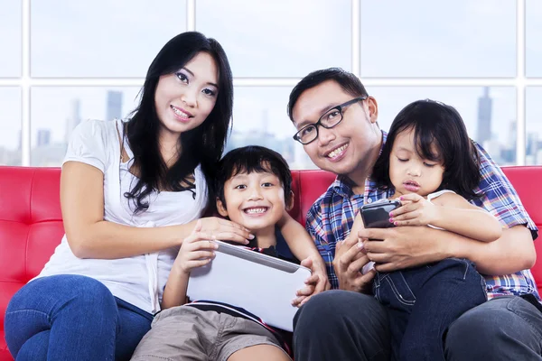 Gelukkige familie op rode sofa in appartement — Stockfoto