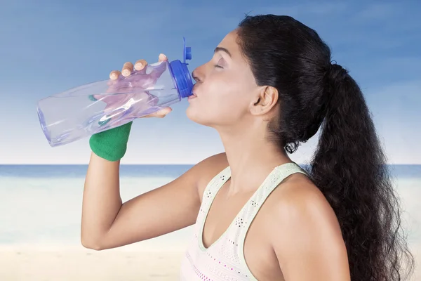 Femme indienne boire de l'eau à la plage — Photo