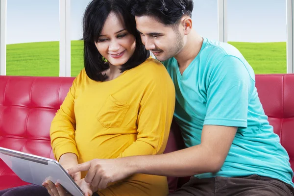 Joyful pregnant couple using tablet — Stock Photo, Image