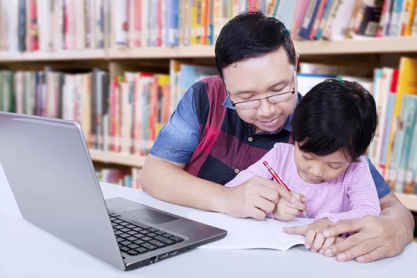 Hombre guía a una chica para escribir en el libro — Foto de Stock