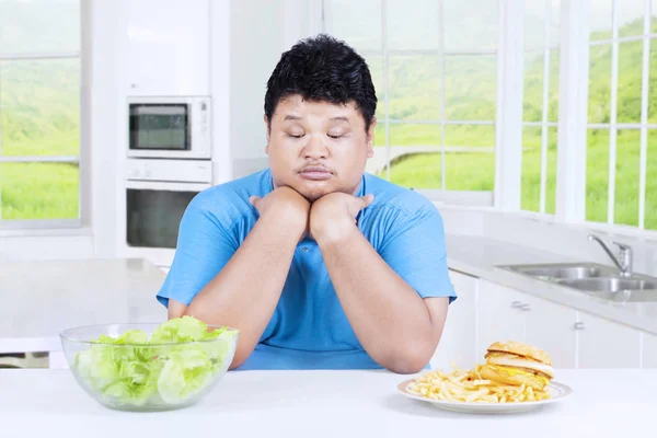 Homem confuso para escolher salada ou hambúrguer — Fotografia de Stock