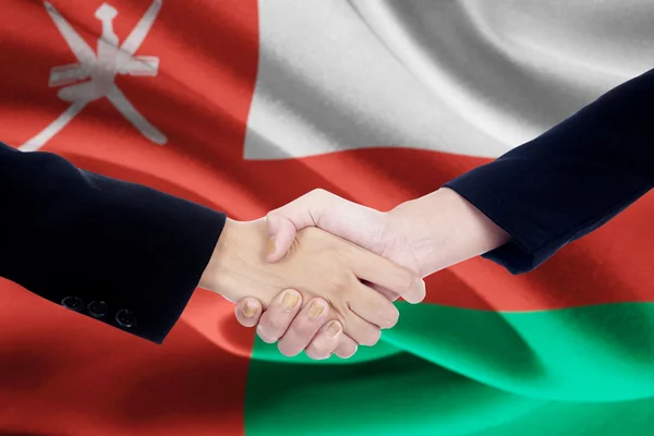 Encontro aperto de mão com bandeira Omã — Fotografia de Stock