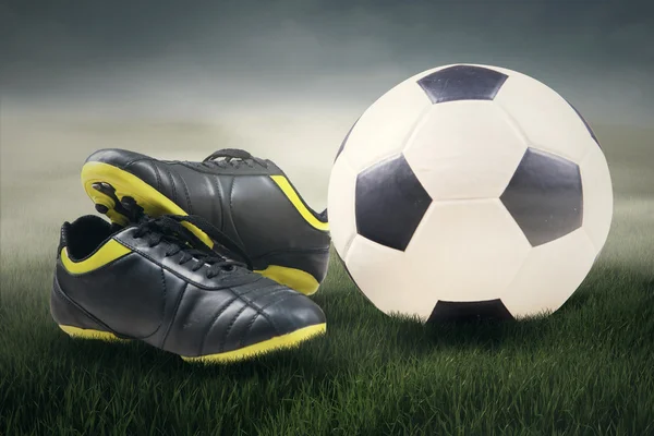 Soccer ball and shoes in grass — Stock Photo, Image