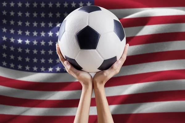 Braços segurando bola com bandeira da América — Fotografia de Stock