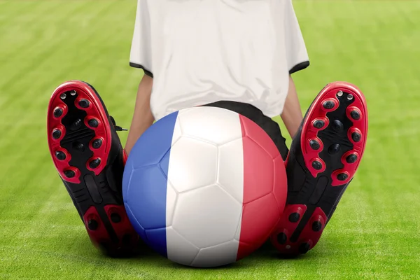 Fotbollsspelare med bollen sitter på ängen — Stockfoto