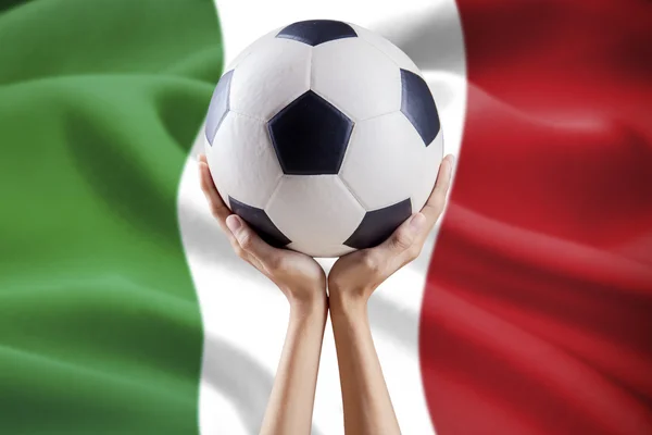 มือถือลูกบอลที่มีพื้นหลังธงของอิตาลี — ภาพถ่ายสต็อก
