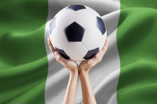 Руки держат мяч с флагом Нигерии — стоковое фото