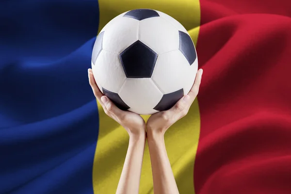 Ręce trzyma piłkę z flagą Rumunii — Zdjęcie stockowe