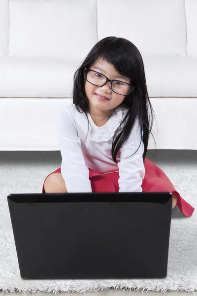 Adorable girl using notebook on the carpet — Stock Photo, Image