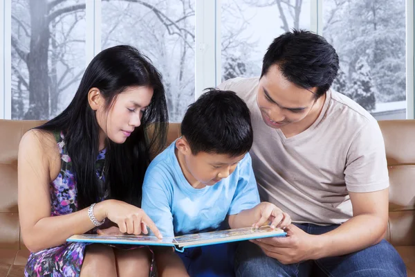 Attraktive Familie liest Bilderbuch auf der Couch — Stockfoto