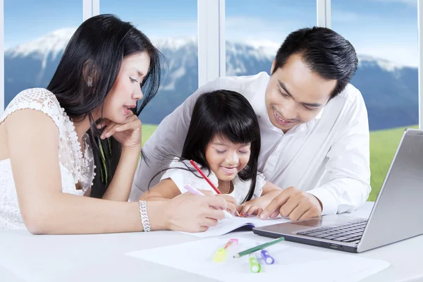 Petite fille faisant des travaux scolaires avec ses parents — Photo