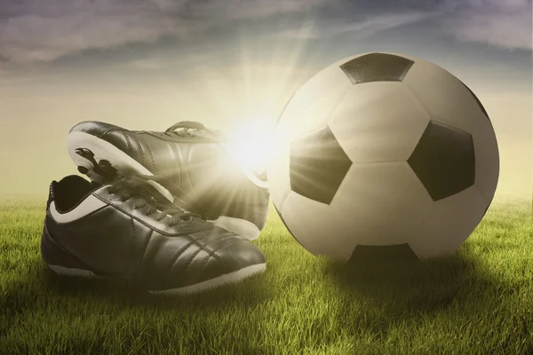 Soccer ball and shoes on the meadow — Stock Photo, Image