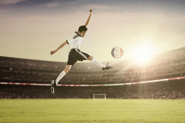 Jugador de fútbol salta mientras patea la pelota —  Fotos de Stock