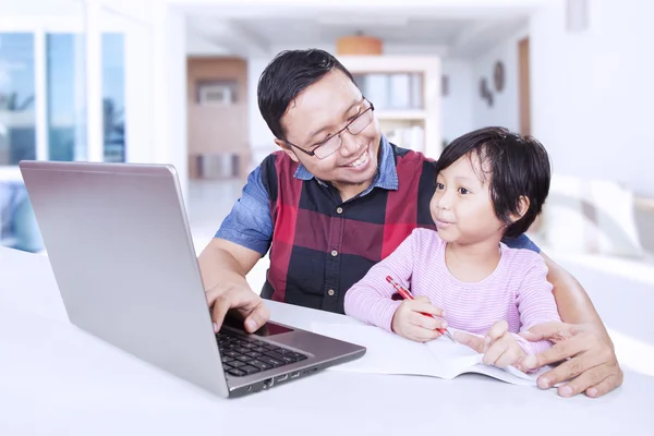 Niña estudiando con su padre en casa —  Fotos de Stock