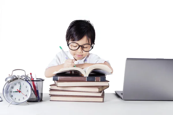 Menina bonito escreve no livro na mesa — Fotografia de Stock