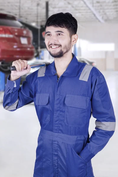 Mannelijke monteur houdt een hulpmiddel in werkplaats — Stockfoto