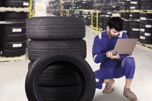 Mecânico usando um laptop para verificar pneus — Fotografia de Stock