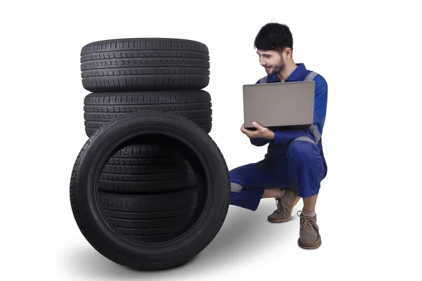 Mecânico com laptop verificando pneus — Fotografia de Stock