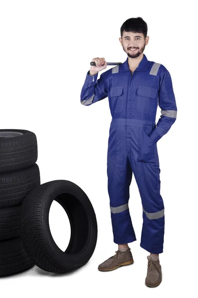 Jovem mecânico com pneus e ferramenta — Fotografia de Stock
