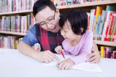 Erkek öğretmen yazmak için küçük bir kız yardımcı olur.