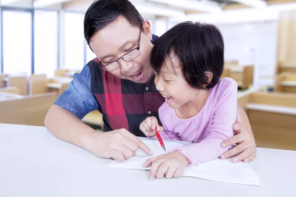 Enseignant aide le petit enfant à écrire sur le livre — Photo