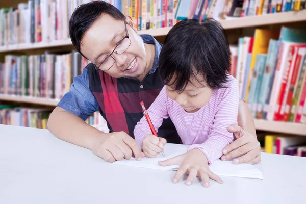 Erkek öğretmen öğrenci yazmak için yardımcı olur.