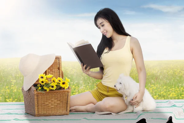 Ragazza legge libro con cane a campo — Foto Stock