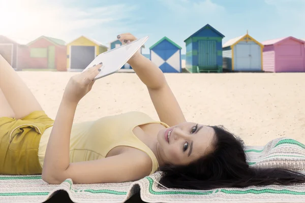 Menina usa tablet enquanto relaxa na praia — Fotografia de Stock