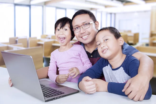 Homem ensinando crianças como usar laptop — Fotografia de Stock