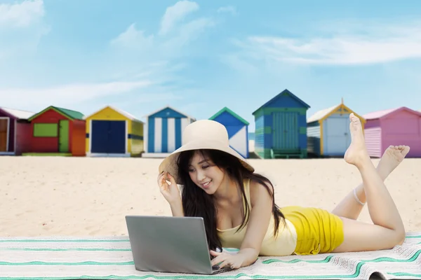 Weibliches Modell nutzt Laptop am Strand — Stockfoto