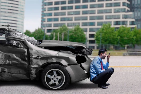 Человек со сломанной машиной говорит по мобильному телефону — стоковое фото