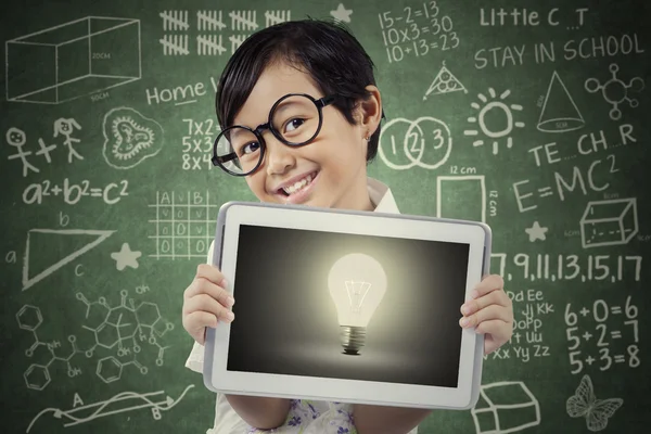 Attractive student shows lightbulb on tablet — Stock Photo, Image