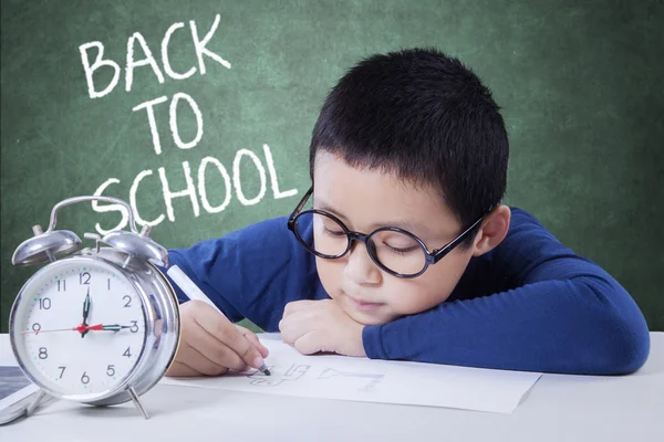 Menino com despertador desenho na classe — Fotografia de Stock