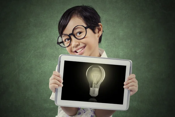 Cute girl holds tablet with lightbulb — Stock Photo, Image