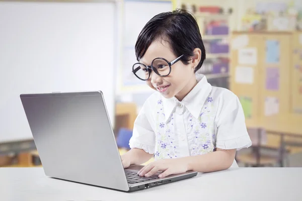 Cute kid learns with notebook in classroom — Stock Photo, Image