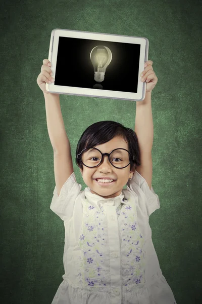 Cute student lifts tablet with lightbulb — Stock Photo, Image