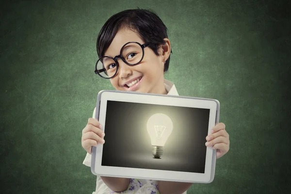 Girl holds tablet with lightbulb and smiling — Stock Photo, Image