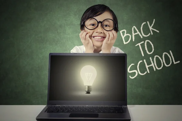 Flicka med laptop och glödlampa i klass — Stockfoto