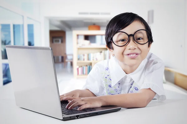 Klein meisje thuis studeren met laptop — Stockfoto