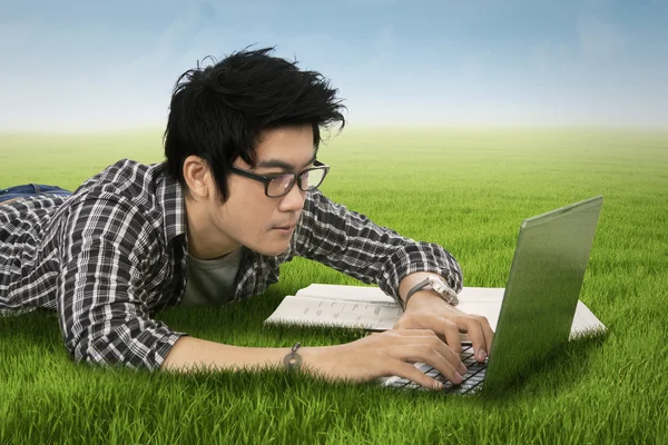 Male student uses laptop in nature — Stock Photo, Image