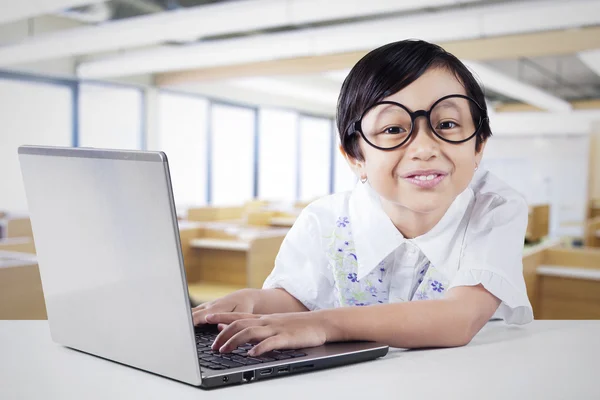 Pretty schoolgirl and laptop in class — Stock Photo, Image