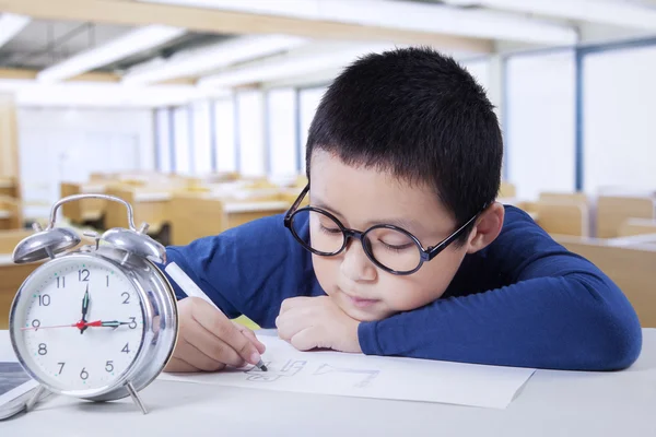 Scholier met wekker in de klas — Stockfoto