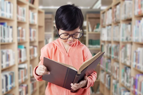 Écolière apprend avec livre dans la bibliothèque — Photo