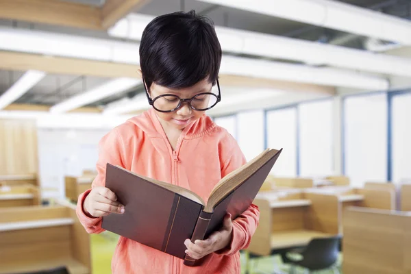 Schoolmeisje leest een boek in de leeszaal — Stockfoto