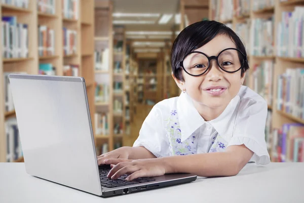 Schoolgirl uses laptop in the library — Stock Photo, Image