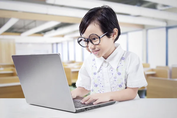 Schoolgirl uses laptop on desk in class — Stock Photo, Image