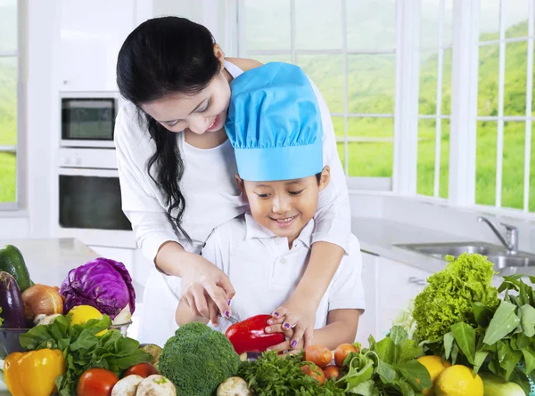 Mulher e seu filho cozinhar legumes — Fotografia de Stock