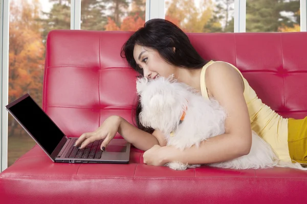 Woman with dog using laptop on sofa — Stock Photo, Image