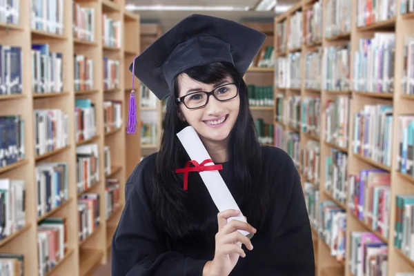 Bacharel alegre com certificado na biblioteca — Fotografia de Stock