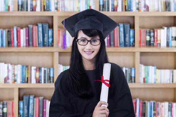 Bachelor holds diploma in library — Stock Photo, Image